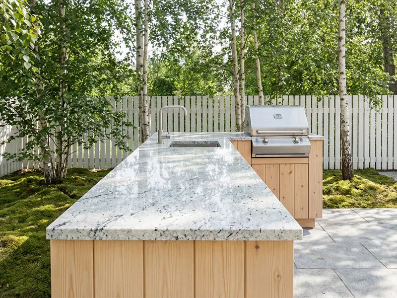 Die Arbeitsplatten für die Außenküche bestehen aus hellem Stein.